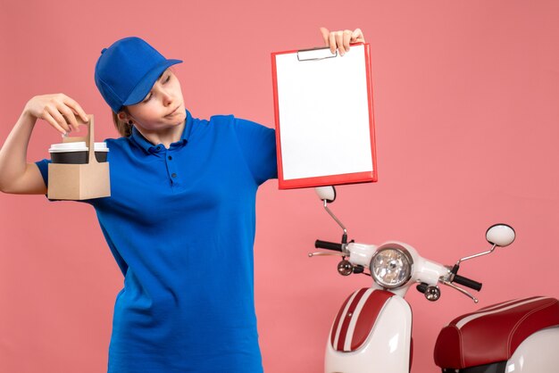 Vista frontal de mensajería femenina con café y nota de archivo sobre el servicio de uniforme de entrega de trabajo rosa trabajador de trabajo pizza mujer bicicleta