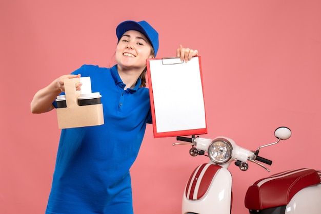 Vista frontal de mensajería femenina con café y nota de archivo sobre el servicio de uniforme de entrega de trabajo rosa trabajador de trabajo pizza mujer bicicleta