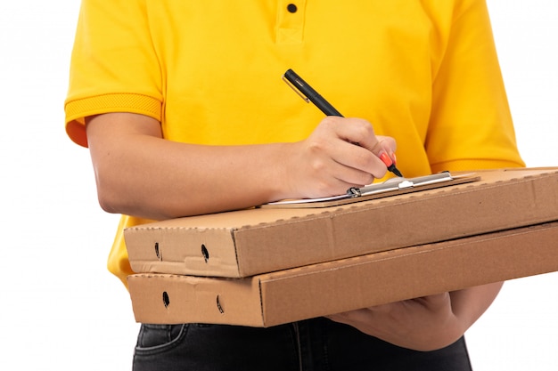 Una vista frontal de mensajería femenina en camisa amarilla gorra amarilla y jeans negros con cajas de pizza orden de escritura en blanco