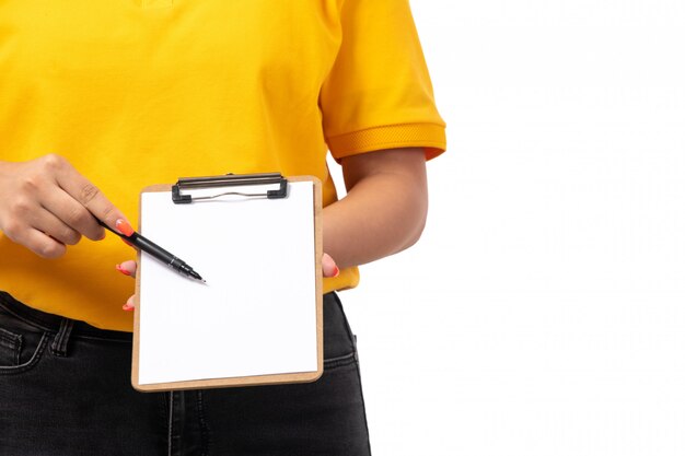 Foto gratuita una vista frontal de mensajería femenina en camisa amarilla gorra amarilla jeans negros con papel y lápiz sobre blanco