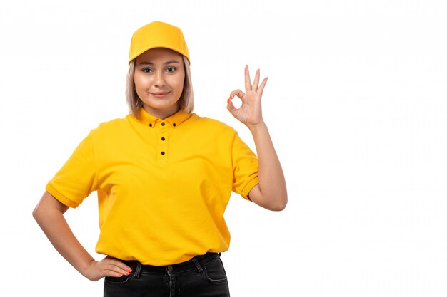 Una vista frontal de mensajería femenina en camisa amarilla gorra amarilla jeans negros sonriendo en blanco
