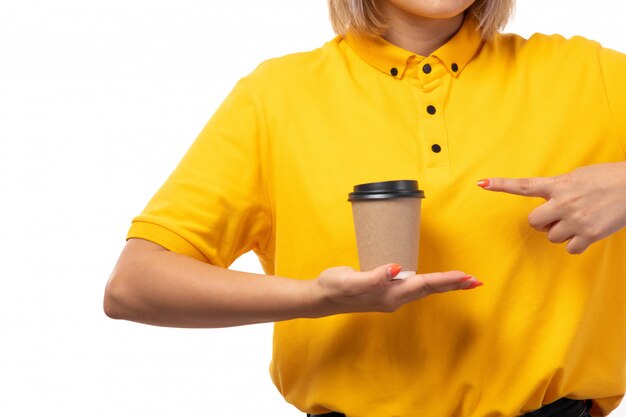 Una vista frontal de mensajería femenina en camisa amarilla con taza de café en blanco
