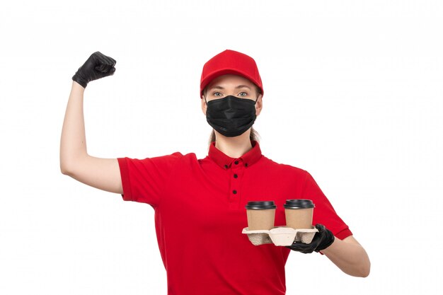 Una vista frontal de mensajería femenina en camisa roja gorra roja guantes negros y máscara negra con café y flexión