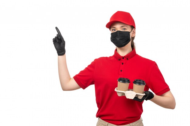 Una vista frontal de mensajería femenina en camisa roja gorra roja guantes negros y máscara negra con café