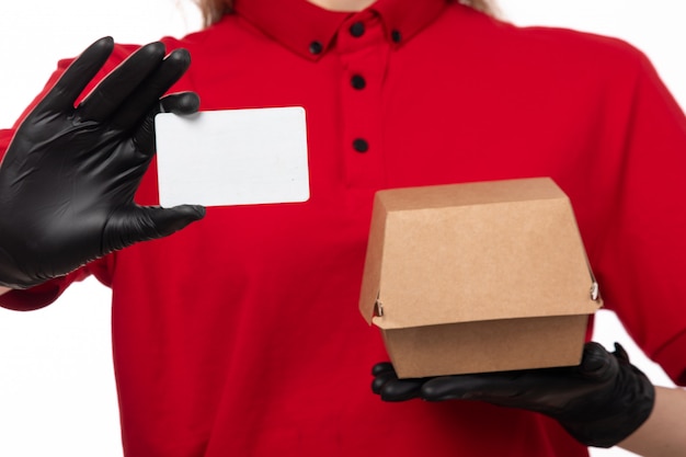 Una vista frontal de mensajería femenina en camisa roja guantes negros con paquete de tarjeta blanca sobre blanco