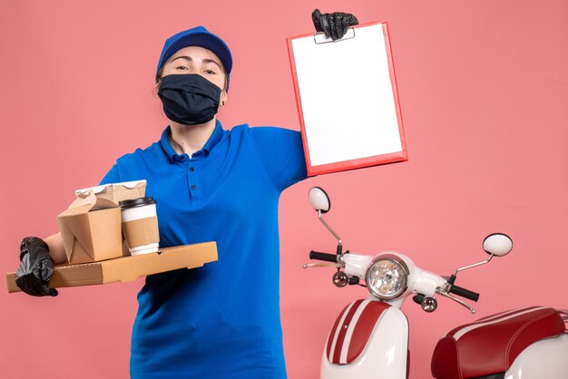 Vista frontal de mensajería femenina con entrega de café y comida en pandemia rosa trabajador del servicio de entrega de trabajo covid- trabajo uniforme