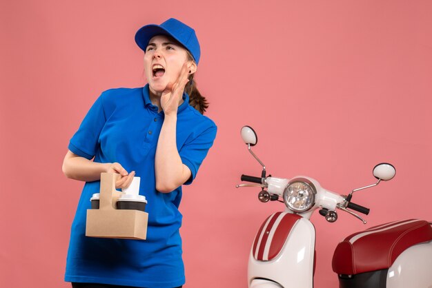 Vista frontal de mensajería femenina con entrega de café en el trabajo de color rosa trabajador de servicio de entrega mujer trabajo uniforme en bicicleta