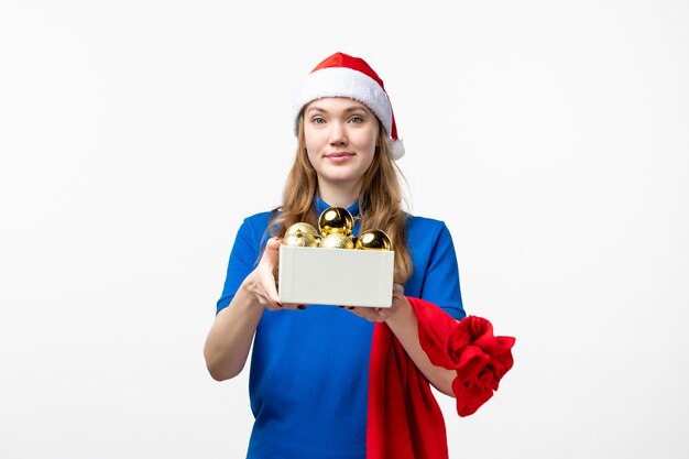 Vista frontal del mensajero femenino con juguetes navideños en la pared blanca