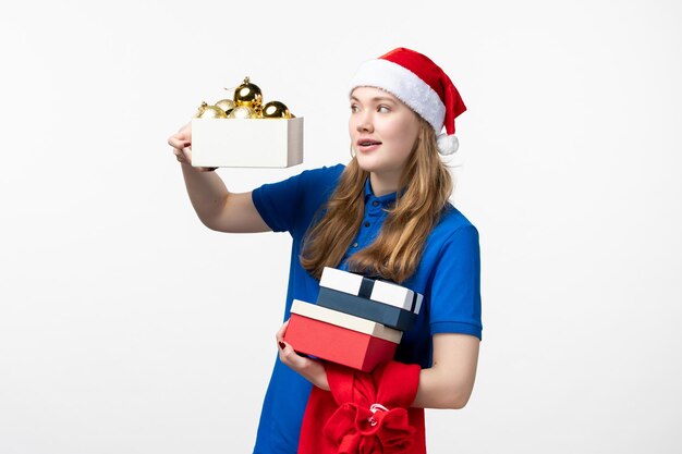 Vista frontal del mensajero femenino con juguetes y regalos en la pared blanca