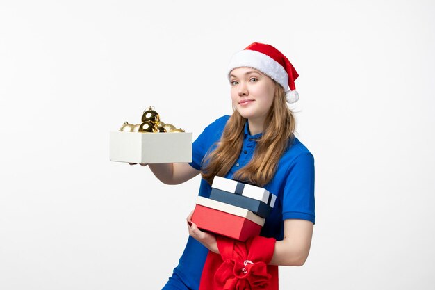 Vista frontal del mensajero femenino con juguetes y regalos en la pared blanca