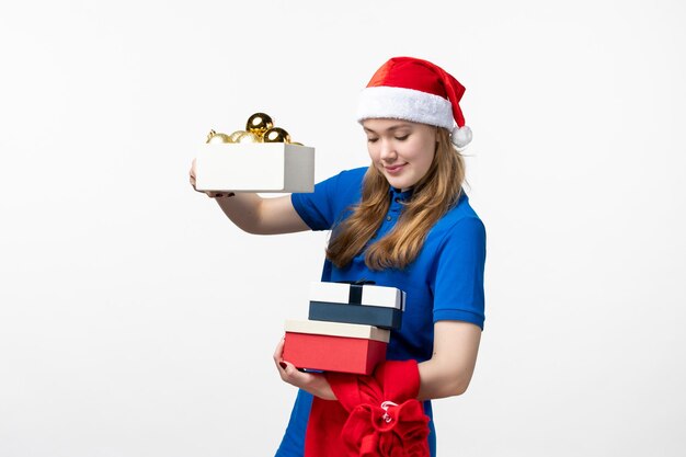 Vista frontal del mensajero femenino con juguetes y regalos en la pared blanca