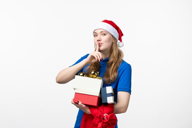 Vista frontal del mensajero femenino con regalos y juguetes en la pared blanca