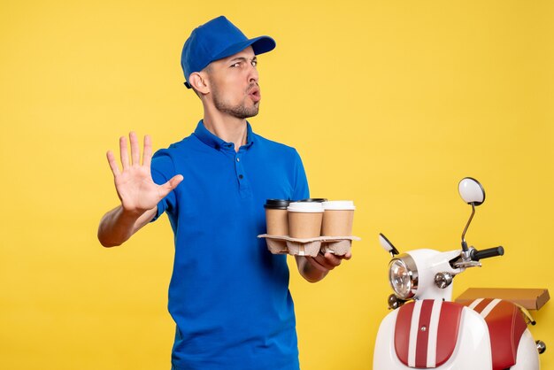 Foto gratuita vista frontal mensajero masculino con entrega de café en servicio de color amarillo trabajo emoción entrega uniforme bicicleta