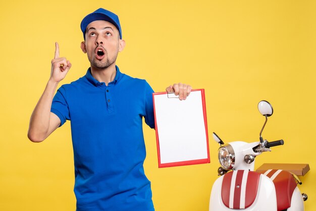 Vista frontal mensajero masculino sosteniendo nota de archivo en color amarillo trabajador servicio uniforme trabajo emoción