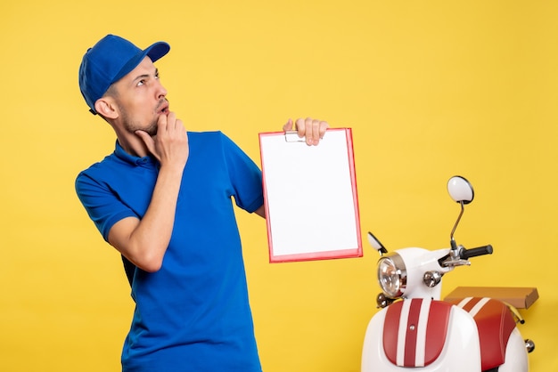 Vista frontal mensajero masculino sosteniendo nota de archivo pensando en color amarillo trabajador uniforme servicio bicicleta trabajo emoción