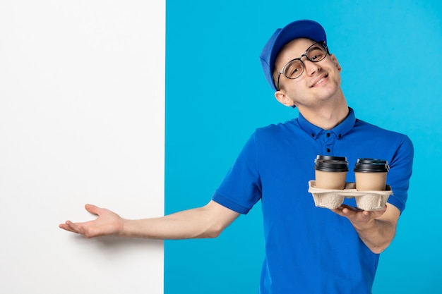 Vista frontal del mensajero masculino en uniforme azul con café en azul