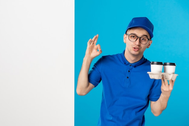 Vista frontal del mensajero masculino en uniforme azul con café en azul