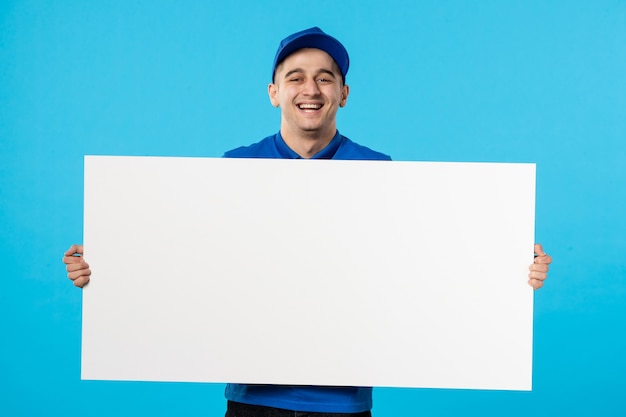 Vista frontal del mensajero masculino en uniforme azul con escritorio liso blanco sobre azul