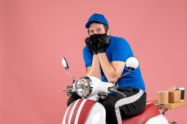 Vista frontal mensajero masculino en uniforme azul y máscara asustada en el trabajo de comida rosa servicio de comida rápida entrega de virus en bicicleta trabajo covid-