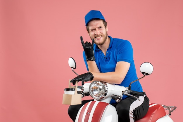 Vista frontal mensajero masculino en uniforme azul sosteniendo café en color rosa trabajador de servicio de bicicleta de entrega de comida rápida de trabajo