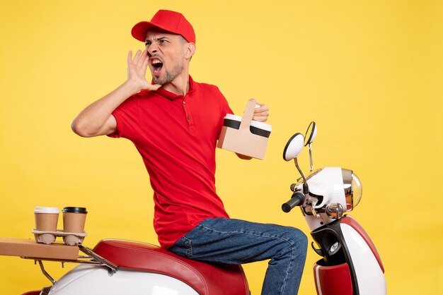 Vista frontal mensajero masculino en uniforme rojo con café en uniforme amarillo trabajo de servicio de trabajador de trabajo de color de bicicleta