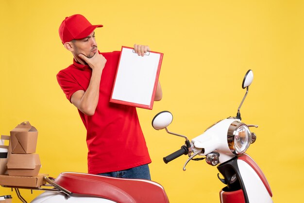 Vista frontal mensajero masculino en uniforme rojo sobre amarillo trabajo entrega trabajo en bicicleta trabajador de servicio