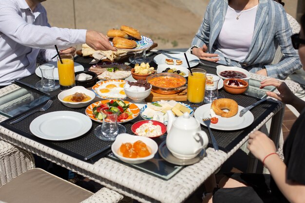 Una vista frontal de la mesa de desayuno personas alrededor de la mesa que comen durante el desayuno de comida durante el día