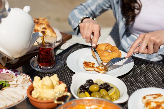 Una vista frontal de la mesa de desayuno personas alrededor de la mesa que comen durante el día desayuno té de comida