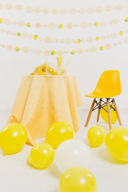 Foto gratuita vista frontal de la mesa y silla con globos y limones