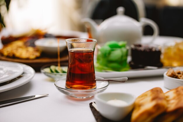 Vista frontal mesa de té dulce con un vaso de armudu de té