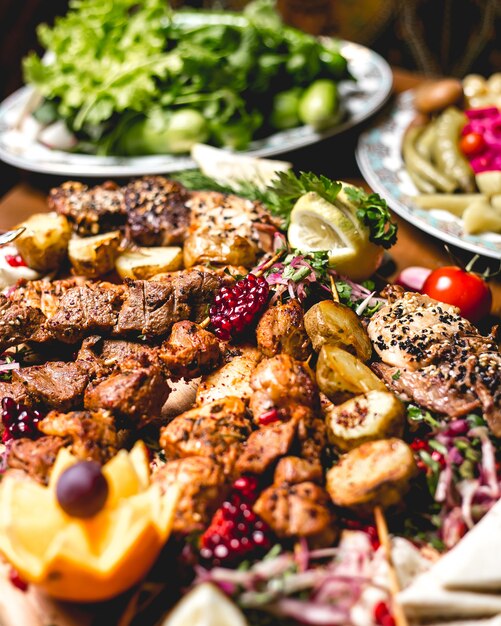 Vista frontal mezclar kebab en brochetas con papas y rodajas de limón