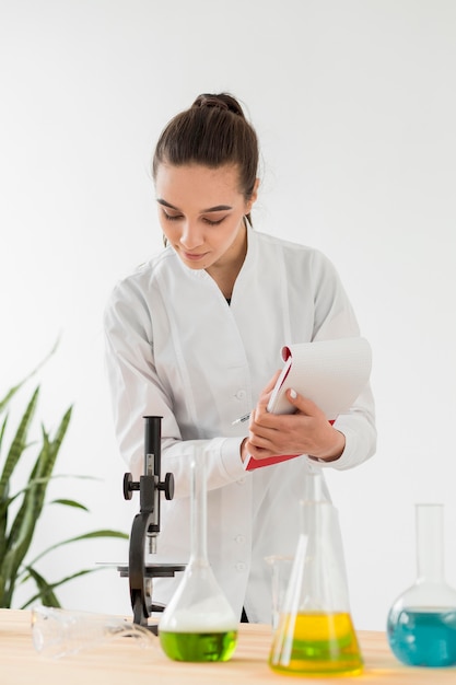 Foto gratuita vista frontal del microscopio de comprobación científico femenino