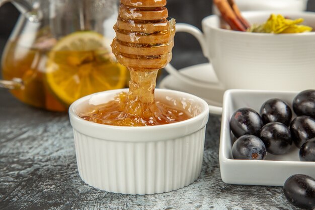 Vista frontal de miel dulce con té y aceitunas en la superficie oscura desayuno de comida de la mañana