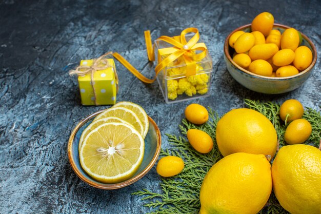 Vista frontal de la mitad y frutas cítricas frescas enteras y cajas de regalo amarillas sobre fondo oscuro