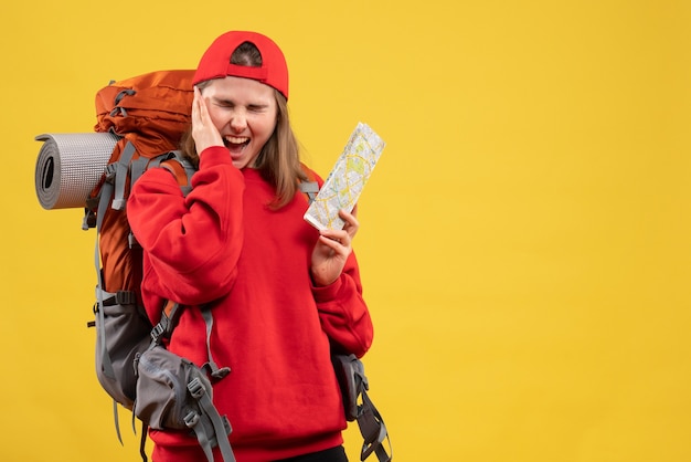Vista frontal mochilero mujer enojada con mapa de viaje sosteniendo su oreja