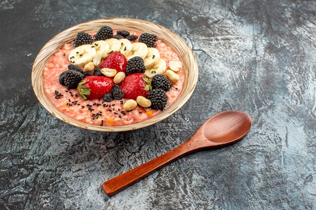 Vista frontal de muesli afrutado con frutas en rodajas en el cereal de desayuno de salud de mesa oscura