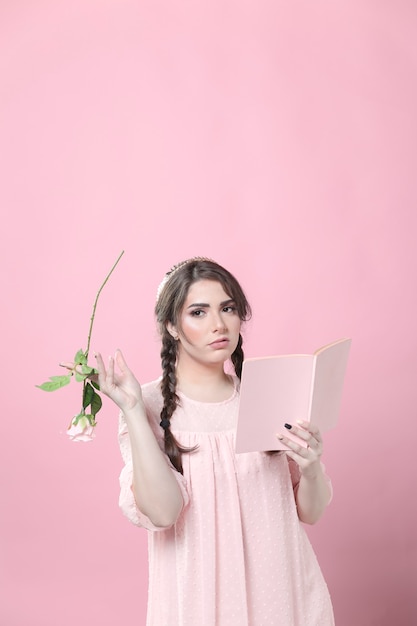 Vista frontal de la mujer aburrida con rosa y libro