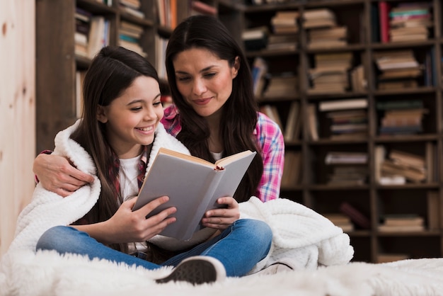 Vista frontal mujer adulta y niña leyendo un libro