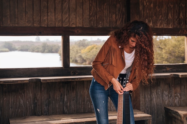 Vista frontal mujer afinando una guitarra