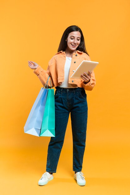 Vista frontal, de, mujer, agujereado, tableta, y, bolsas de compras