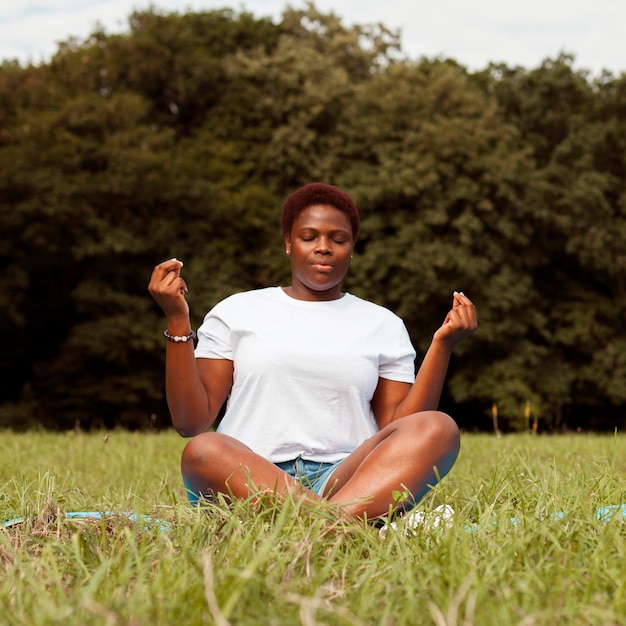 Foto gratuita vista frontal de la mujer al aire libre meditando en la naturaleza