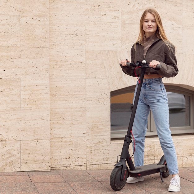 Vista frontal de la mujer al aire libre con scooter eléctrico y espacio de copia