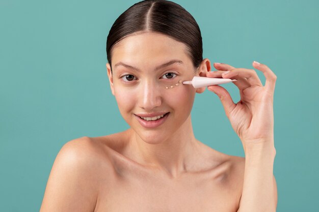 Vista frontal mujer aplicando crema facial