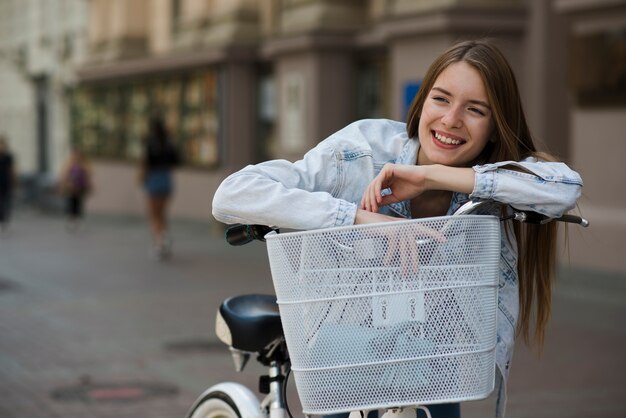 Vista frontal de la mujer apoyada contra el manillar de la bicicleta.
