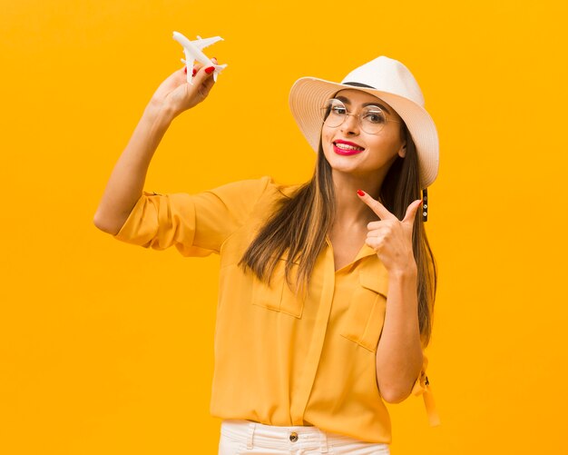 Vista frontal de la mujer apuntando a la figura del avión que está sosteniendo