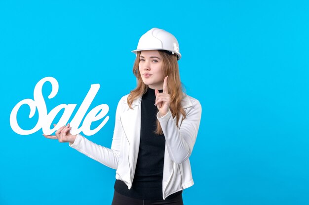 Vista frontal de la mujer arquitecto sosteniendo venta escribiendo advertencia en azul