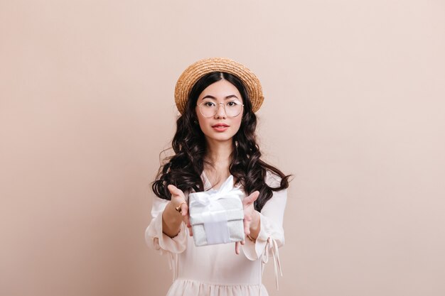 Vista frontal de la mujer asiática con regalo de cumpleaños. Mujer China con sombrero de paja con caja actual.