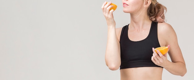 Vista frontal de la mujer atlética disfrutando de una naranja con espacio de copia
