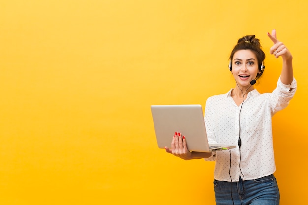 Vista frontal de la mujer con auriculares y apuntando con espacio de copia