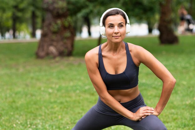 Vista frontal mujer con auriculares haciendo ejercicio